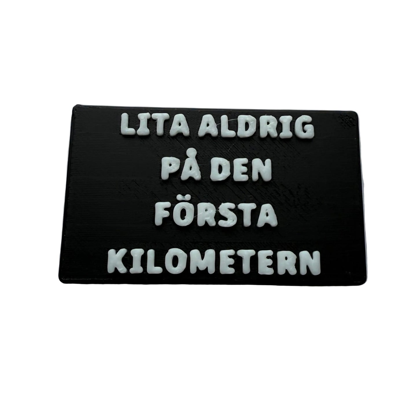 Kylskåpsmagnet med svart bas och vit text